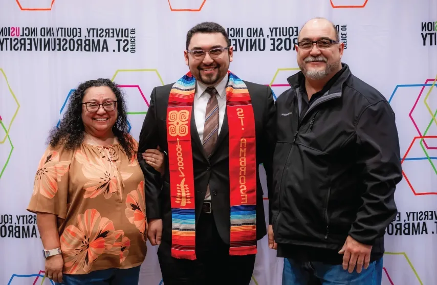 A student with a cultural stole posing with parental figures.